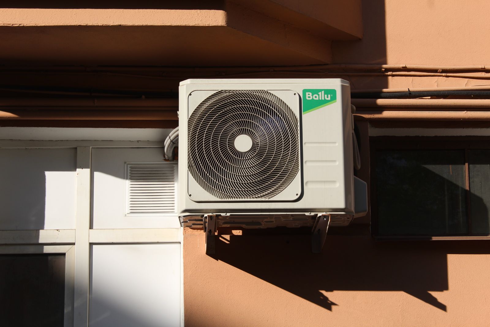 Residential outdoor condenser unit mounted beside a home exterior wall